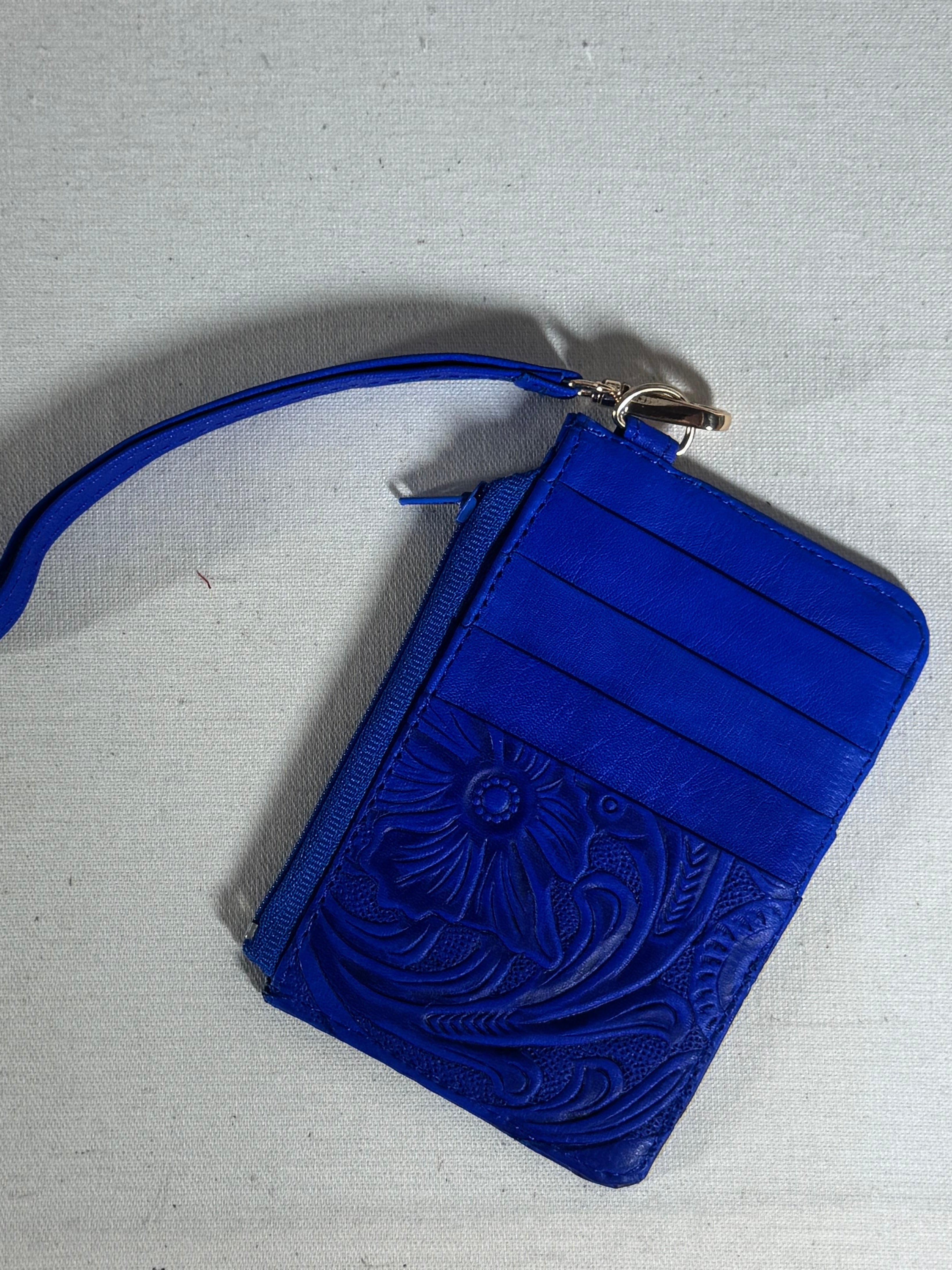 Blue wristlet with floral embossing on a textured surface