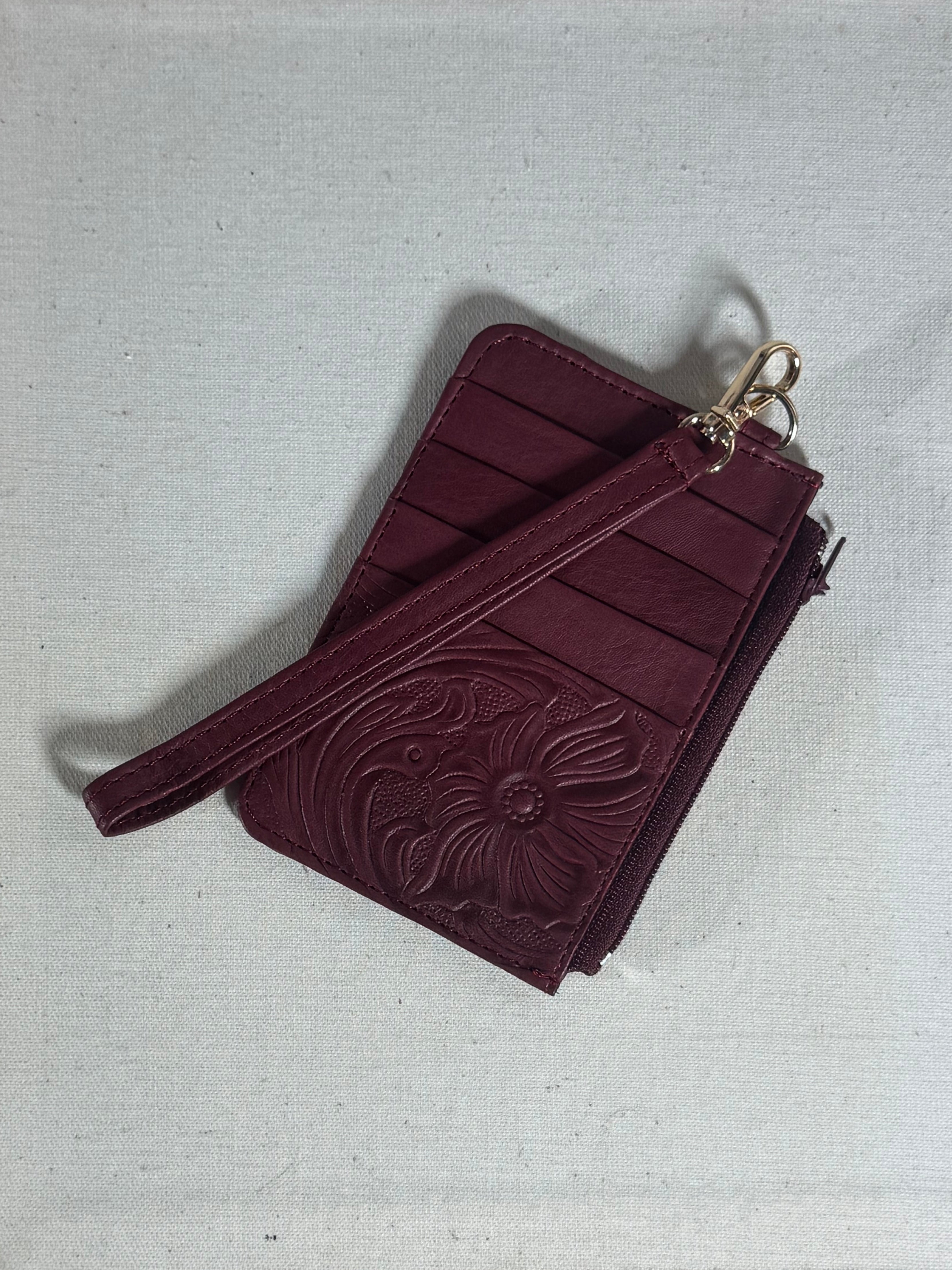 Maroon leather wallet with floral design on a textured surface