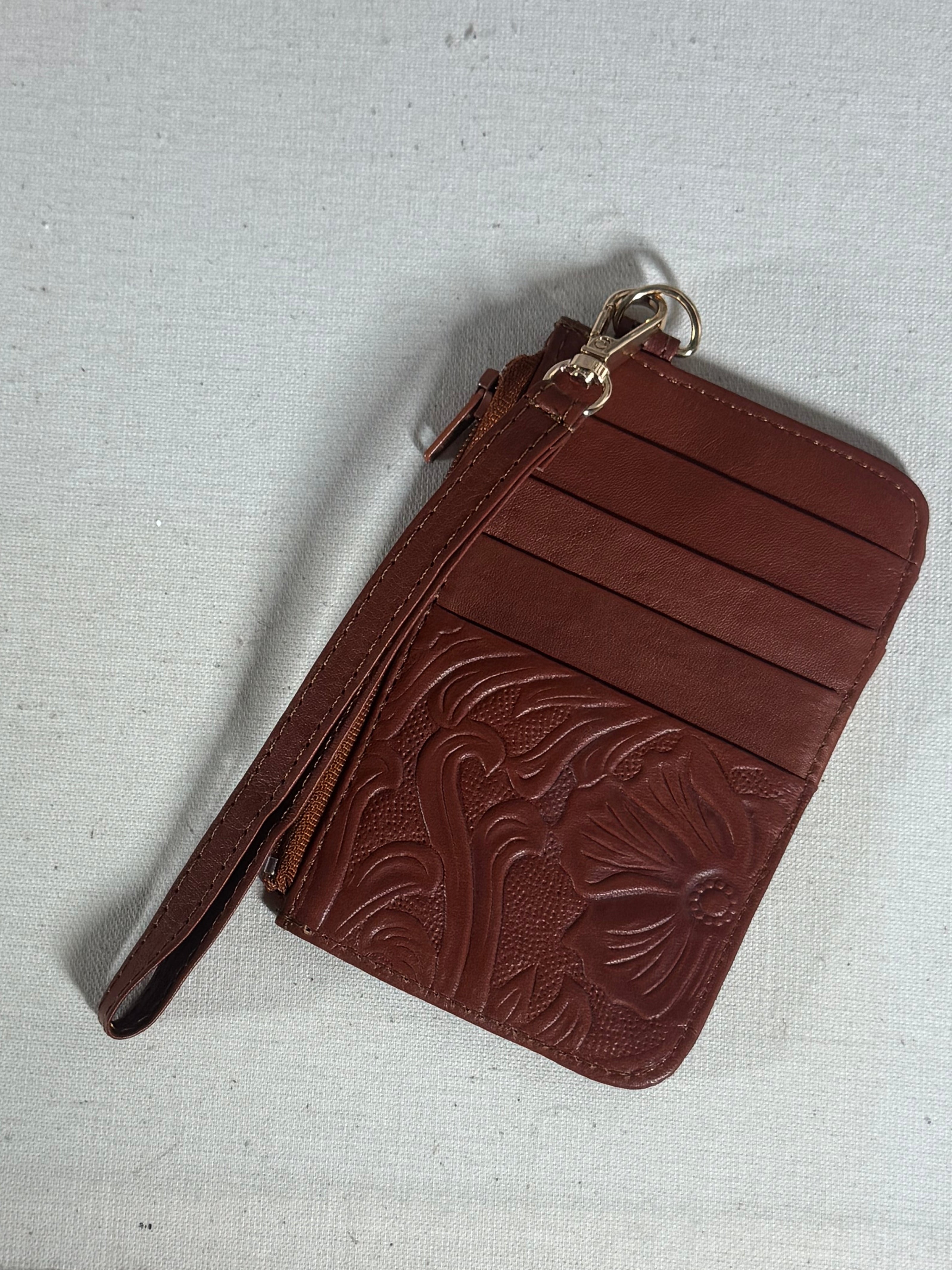 Brown leather wallet with floral embossing on a textured surface