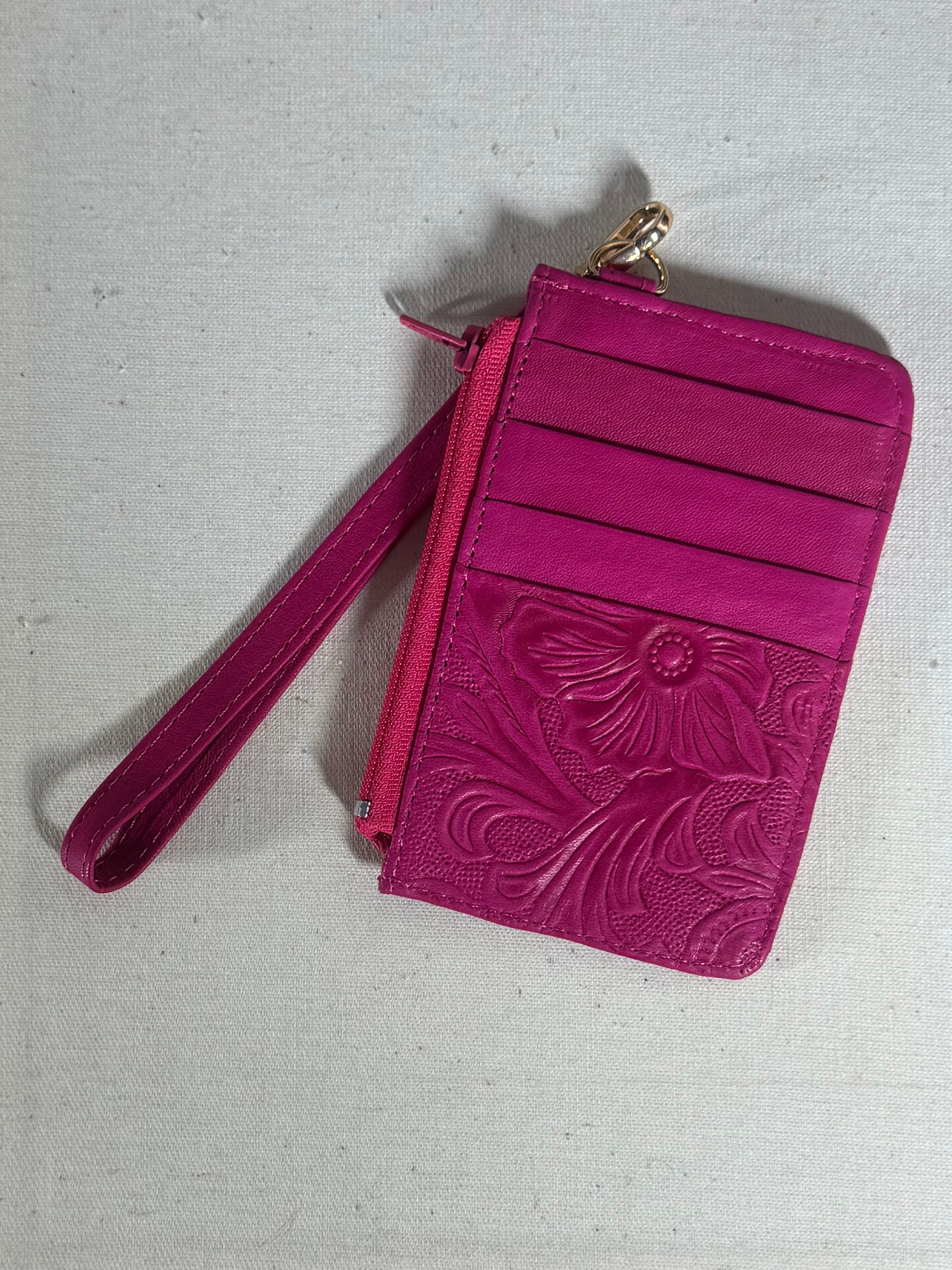 Pink wallet with floral embossing on a textured surface