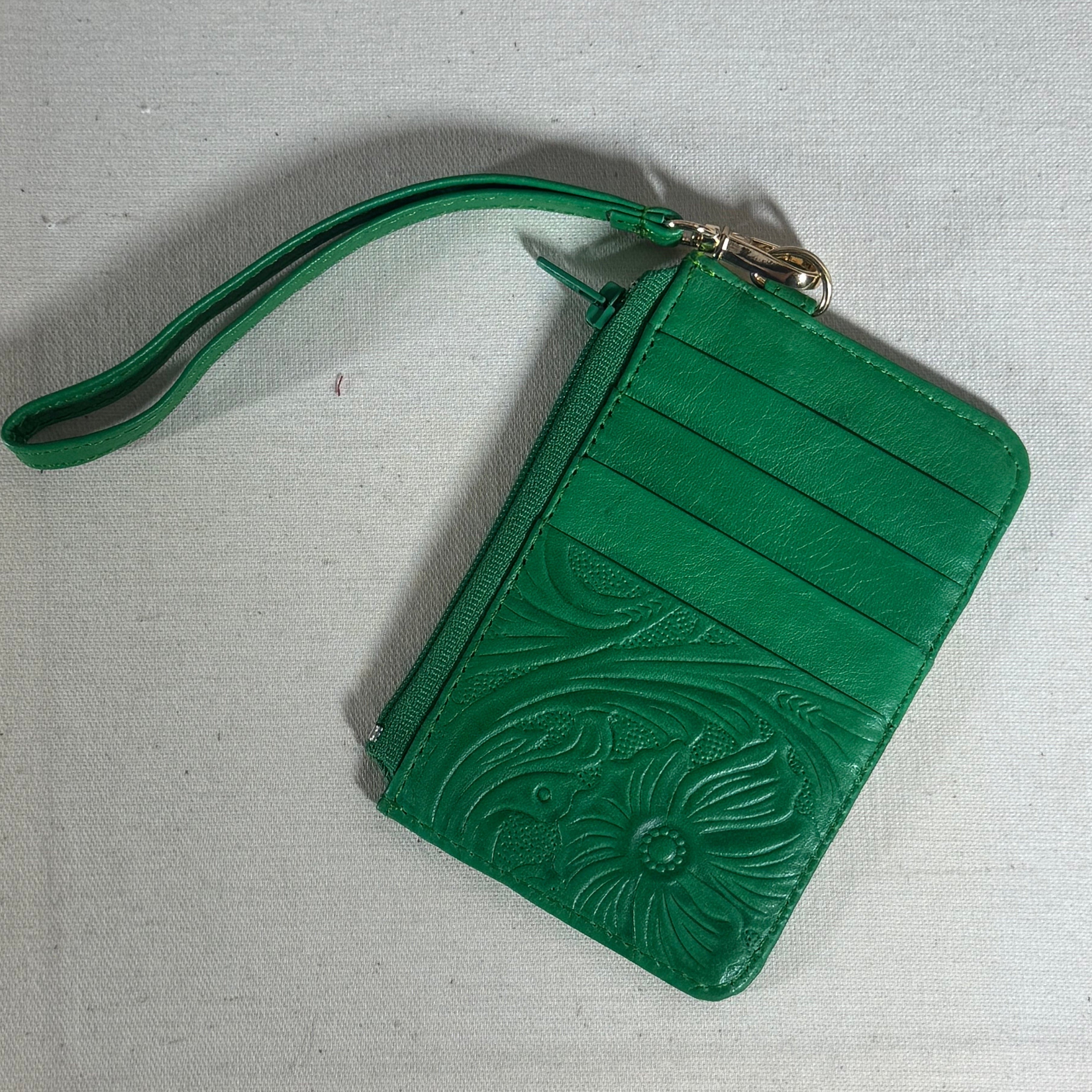 Green wristlet with floral embossing on a textured surface