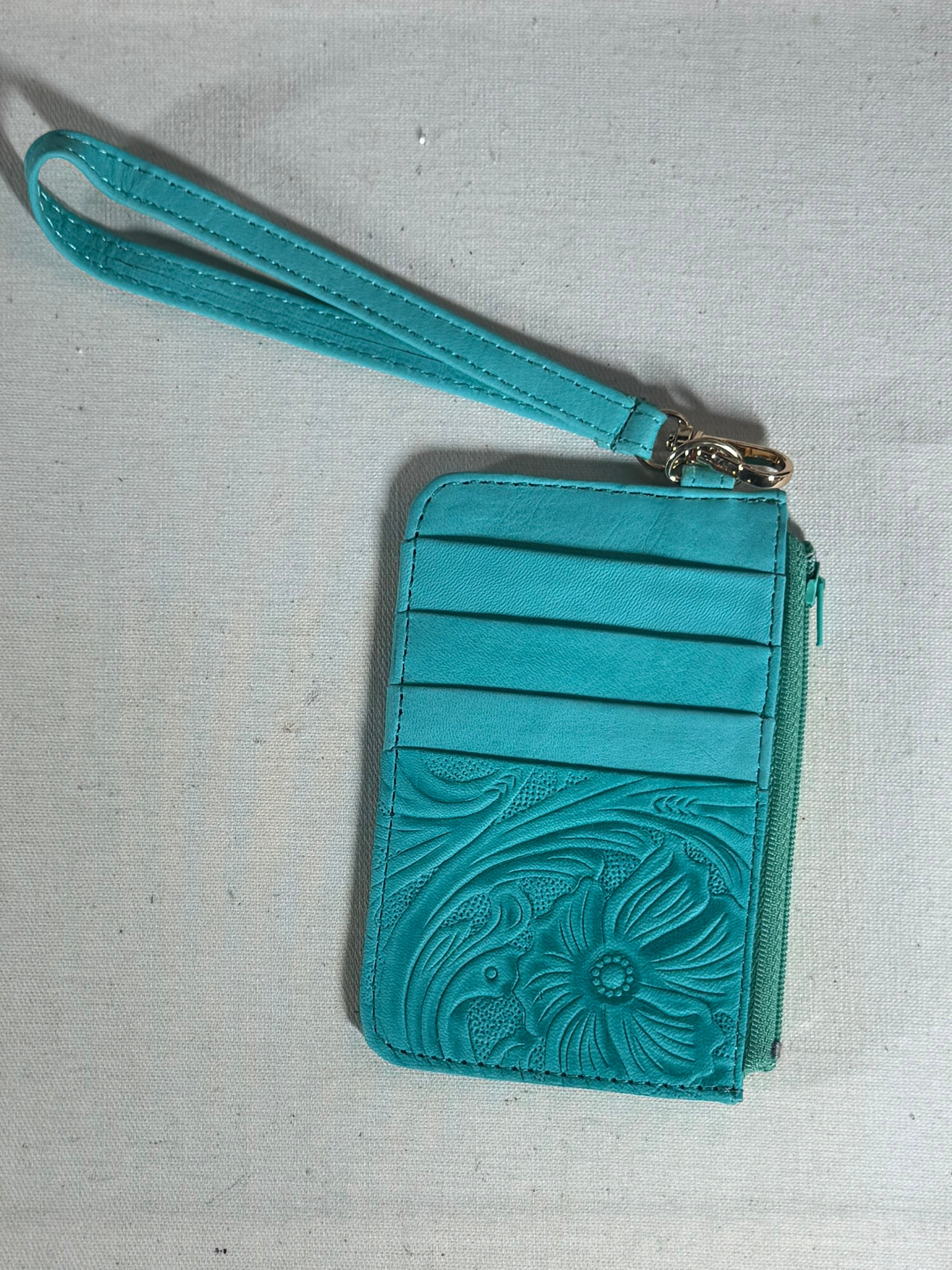 Turquoise wristlet with floral embossing on a textured surface